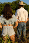 A man and a woman wearing Texas Exes (Pre-Order) belts from the Zilker Belts brand standing in a field.