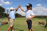 Two boys giving each other high fives on a golf course while wearing ATX Kids belts from Zilker Belts.