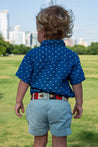 A young boy wearing a Willie Kids shirt and shorts in a park.