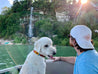 A man on a boat with a dog in front of a waterfall wearing the Zilker Belts Imperial ATX Hat.