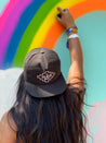 A woman wearing an Antone's Rope Hat by Zilker Belts painting a rainbow on a wall.