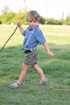 A young boy holding an Argentina Kids stick in a grassy field, made by Zilker Belts.