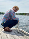 A man wearing Zilker Belts Save Muny crouching on a dock.