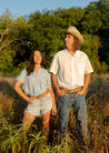 A man and a woman standing in a field of tall grass wearing Texas Exes (Pre-Order) belts from Zilker Belts.