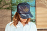 A woman wearing a cool and comfortable Denim "J Willy" Hat (LIMITED EDITION) by Zilker Belts.