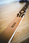 A Vagabond leather belt hand-stitched onto a Zilker Belts wooden table.