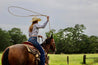 A woman in a cowboy hat is roping a Native horse, using Zilker Belts.