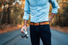 A man standing on a road holding a Zilker Belts ACL camera.