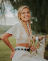 A blonde woman in a white top and white pants is posing for a photo wearing Zilker Belts' Argentina.