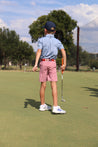 A young boy is wearing Willie Kids Zilker Belts and standing on a golf course.