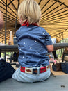 A little boy sitting on a picnic table wearing Zilker Belts' Willie Kids.