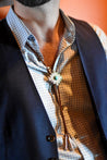 A man is wearing a Zilker Bolo Tie with a blue eye.