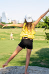 A young girl is flying an Antone's Kids frisbee on a Zilker Belts rock.