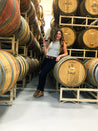 A woman posing in front of rows of Zilker Belts Waterloo barrels.