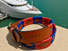 A blue and red Sunshine leather belt with a boat in the background, from Zilker Belts.