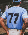 A man wearing a Zilker Belts baseball jersey with the number 77 on it.