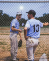 Two baseball players talking near the Moontowers at a baseball field.