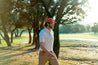 A man wearing a Zilker Belts ATX Rope Hat walking through a park.