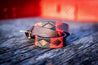 A Raider belt by Zilker Belts, in red and black leather, on a wooden table.